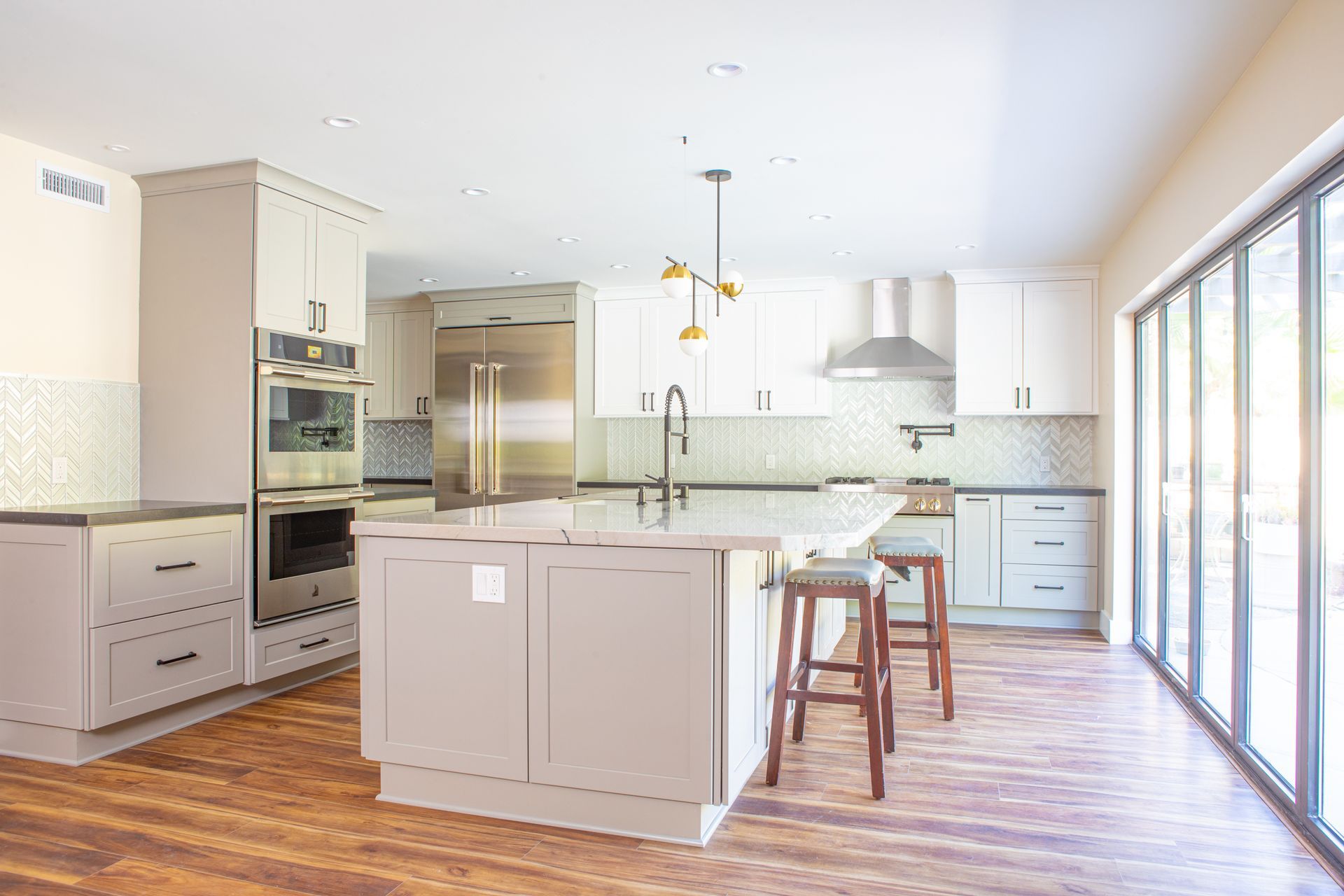 Modern kitchen with a central island, stainless steel appliances, and large glass doors.