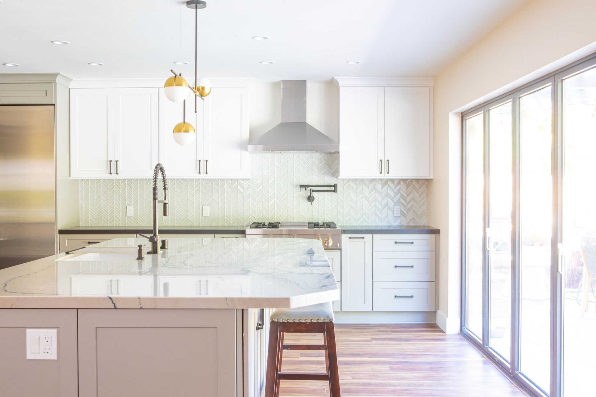 Modern kitchen with white cabinets, gray island, and large windows.