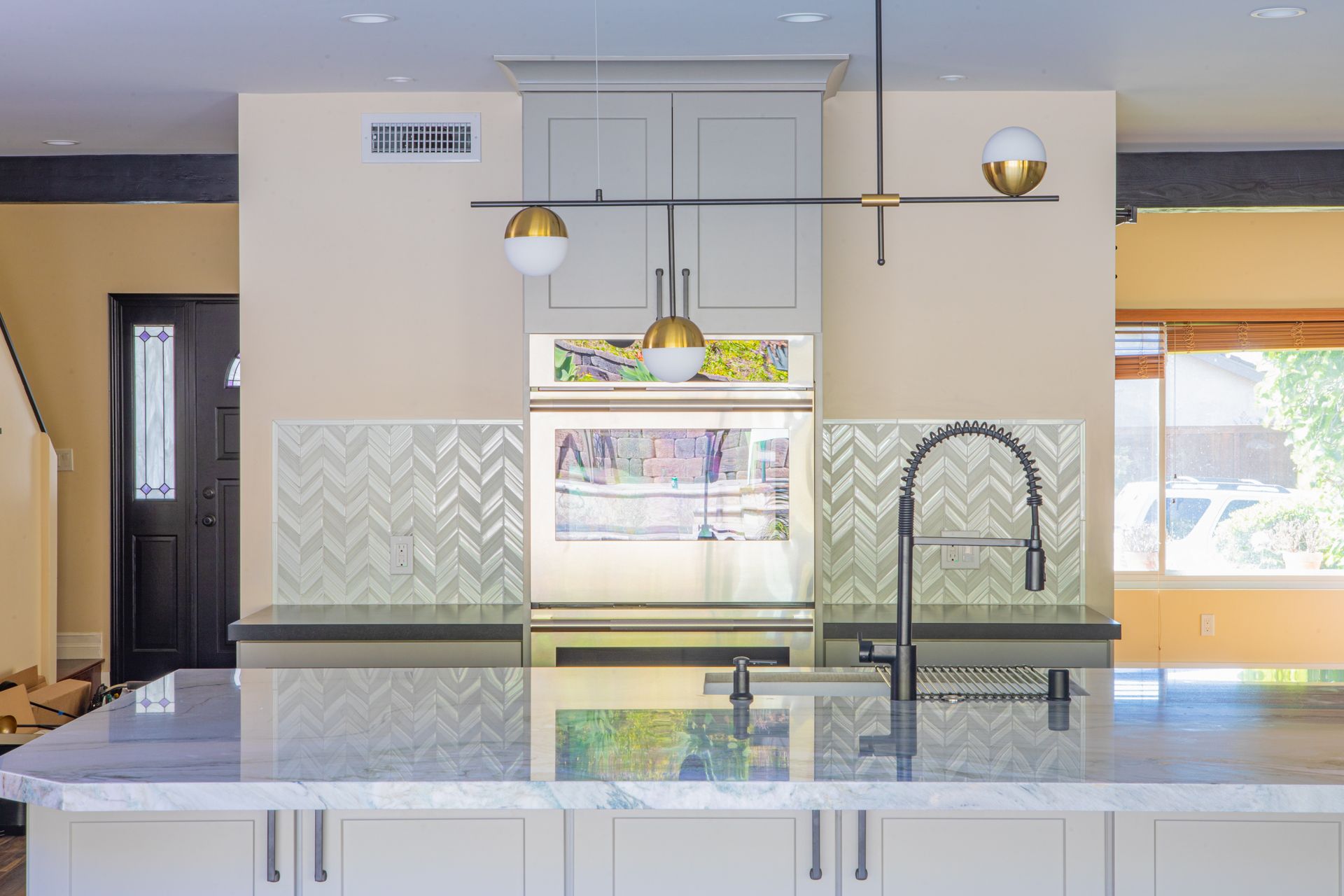 Kitchen interior with gray and white cabinets, wood floor, and window with blinds.