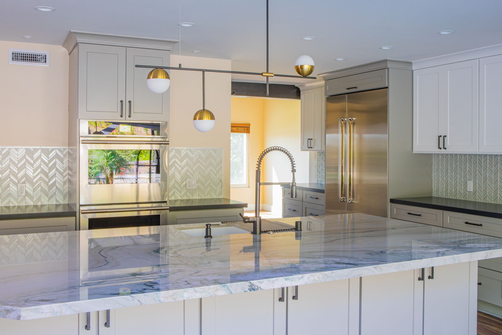 Modern kitchen with a marble island, light cabinets, and gold fixtures.