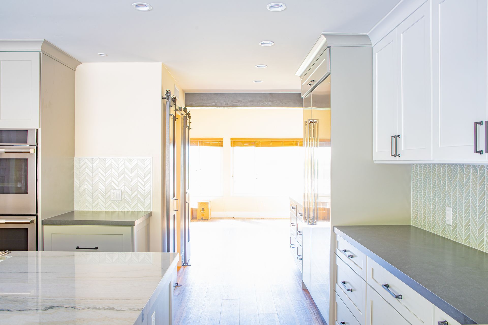 Bright, modern kitchen with white cabinets, gray countertops, and a view to the outside.