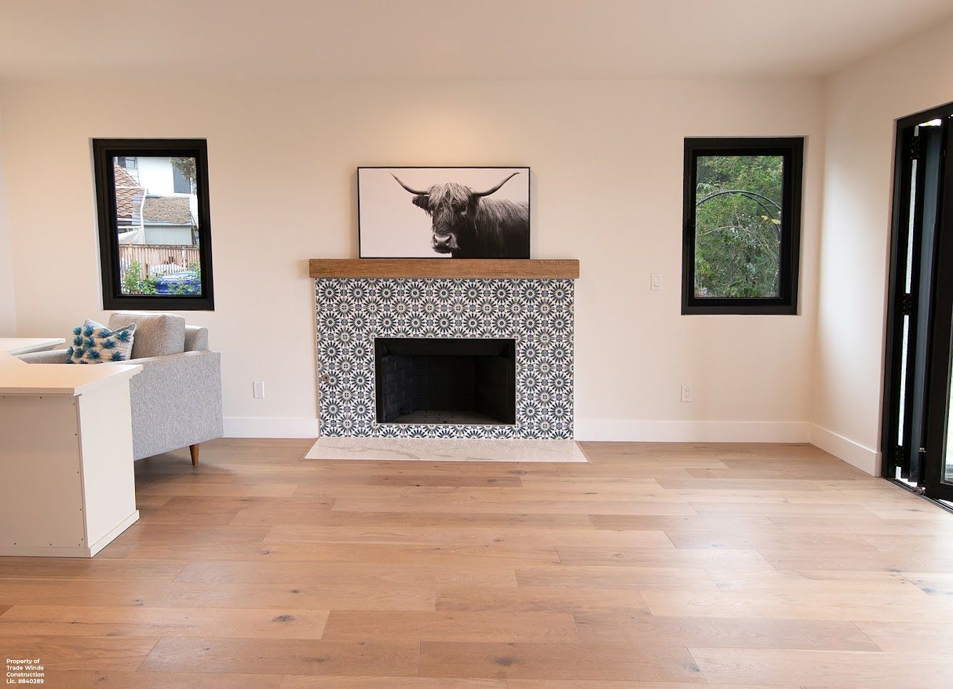 Living room with fireplace, wooden floors, black framed windows, and a Highland cow art piece.