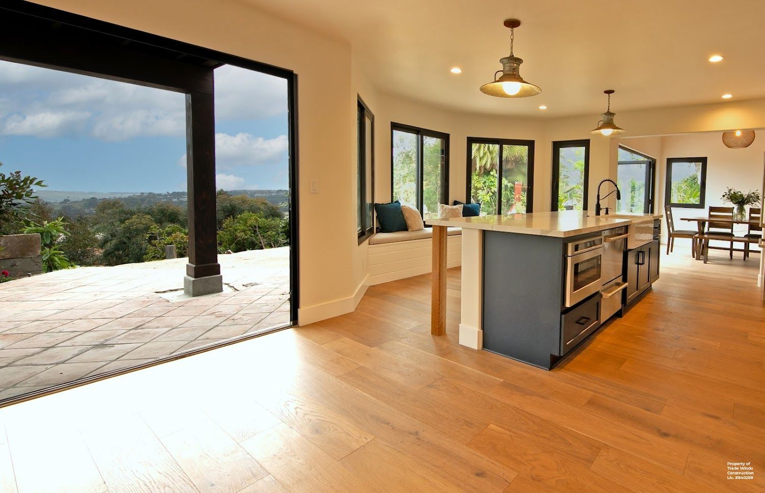 Spacious kitchen with large sliding door to outdoor patio, island with seating, and views of the landscape.