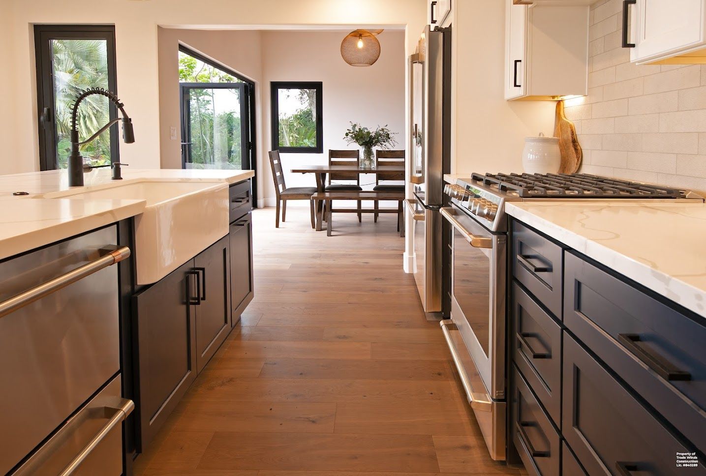 Modern kitchen with dark blue cabinets, light countertops, and a view of the dining area.