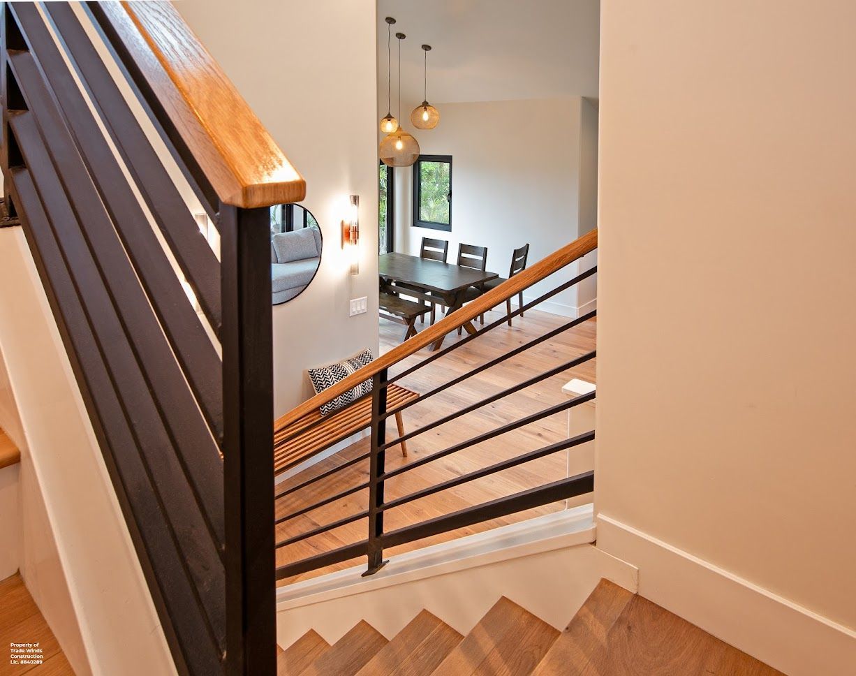 Staircase with wooden steps and black metal railing leading to a dining area with a table and chairs.