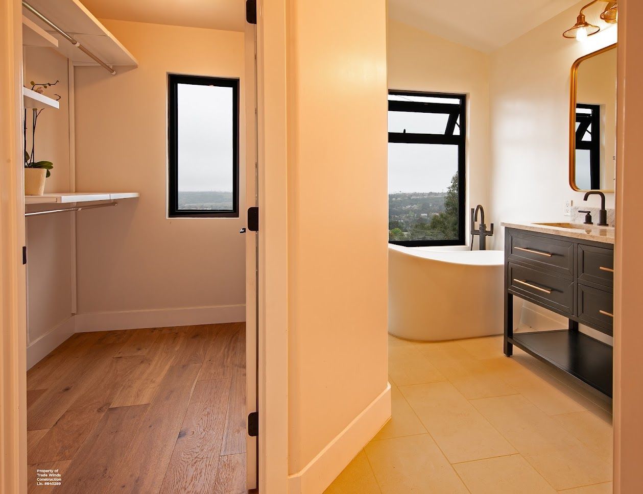 Hallway looking into a walk-in closet and bathroom with a tub and vanity; neutral tones.