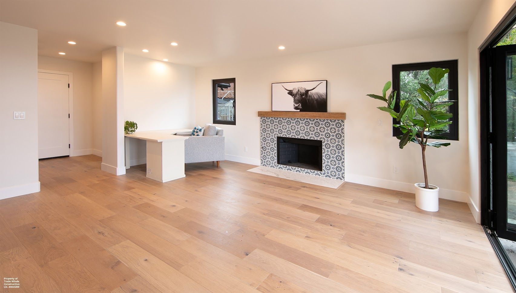 Empty living room with hardwood floors, fireplace, and large windows; a modern, bright space.