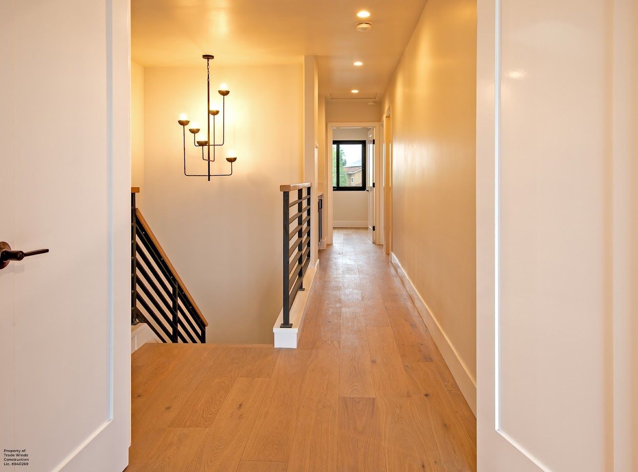 Hallway with wooden floor, staircase, and decorative light fixture.