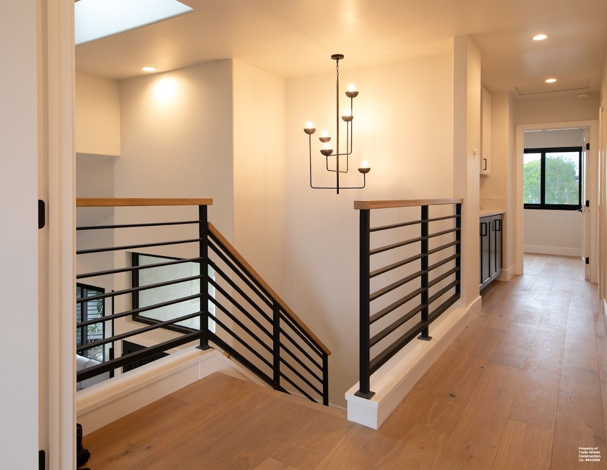 Modern home interior with a staircase, hardwood floors, and a decorative chandelier.