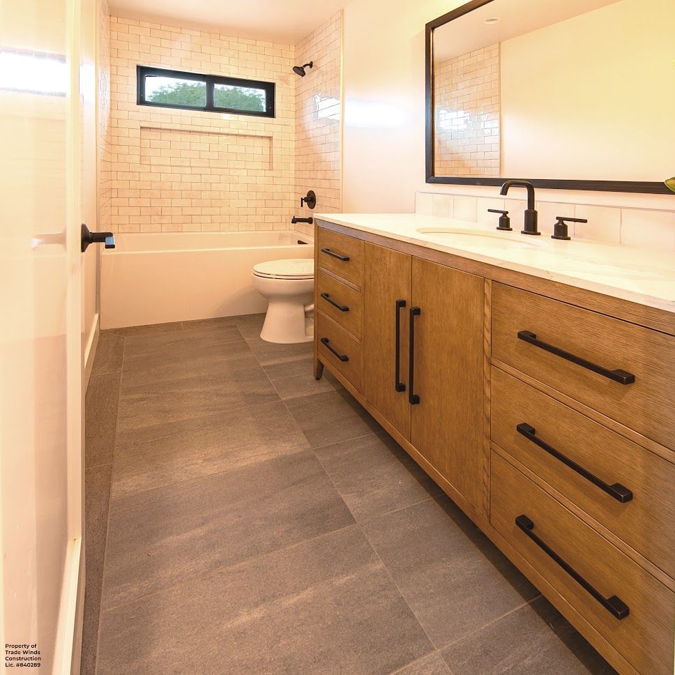 Bathroom with wood vanity, white subway tile, gray floor tile, and black fixtures.