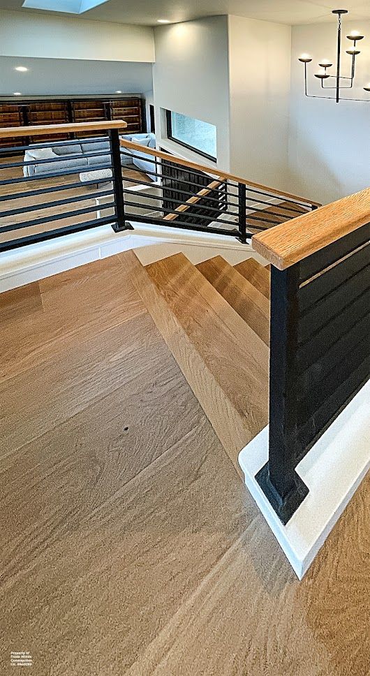 Wooden staircase with black railing and light wood handrail.