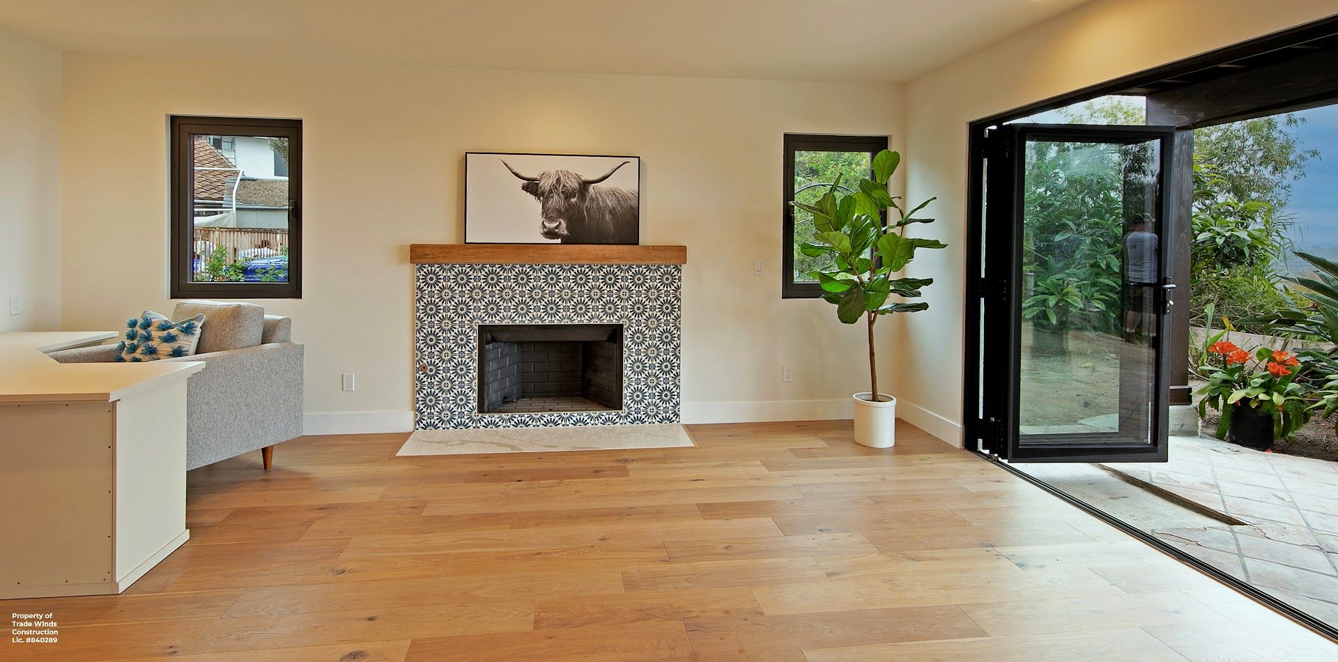 Open living room with fireplace, hardwood floors, and open glass doors leading to an outdoor patio.