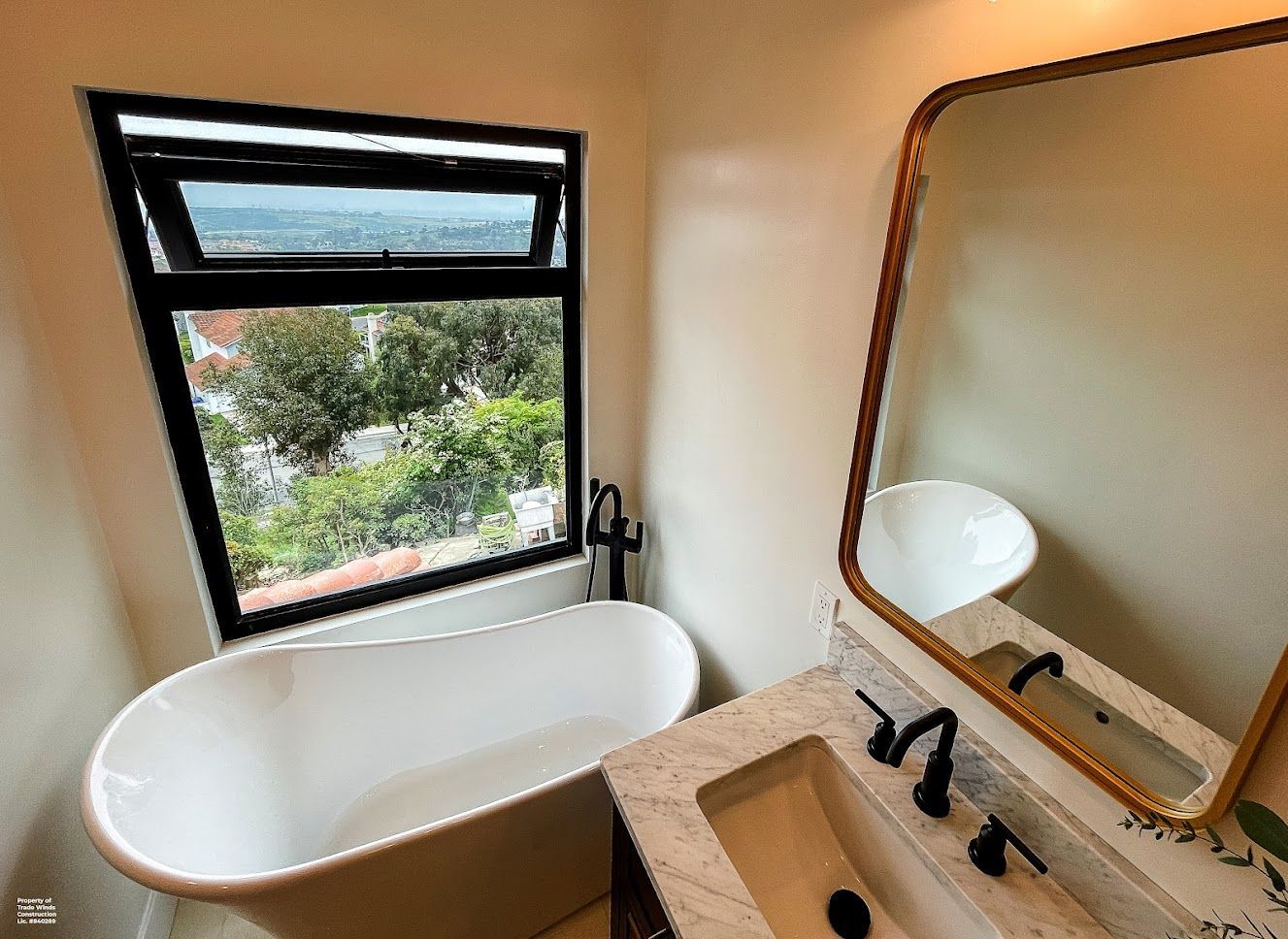 Bathroom with a white clawfoot tub, vanity, large mirror, and a window with an outdoor view.
