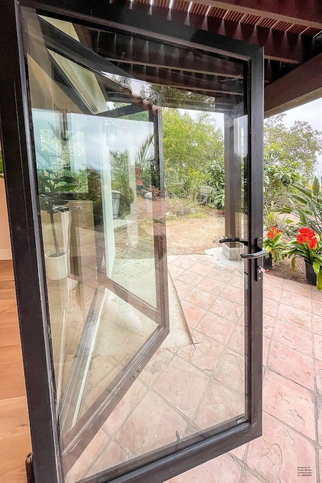 Black-framed glass French doors open to an outdoor patio with greenery.