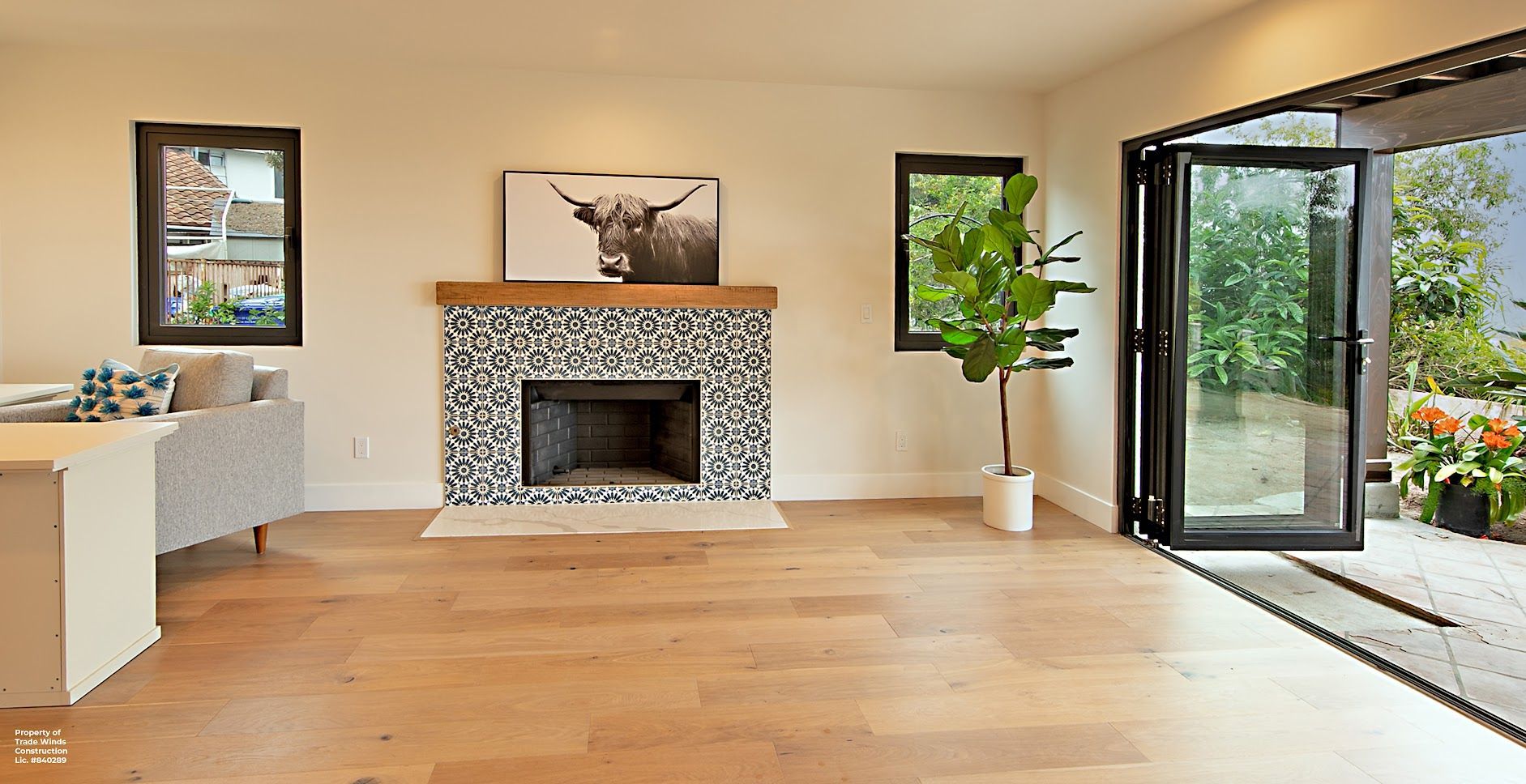 Living room with fireplace, wood floors, and folding glass doors leading to the outdoors.