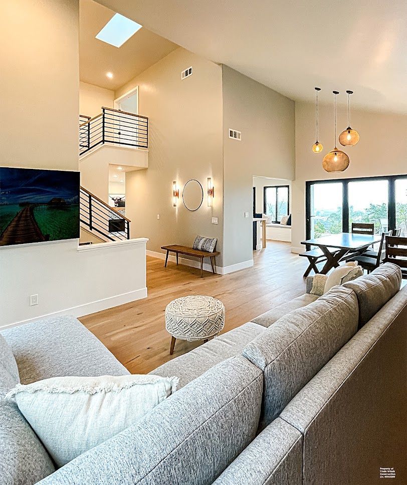 Modern living room with light-colored walls, wood floors, and a large gray sectional.