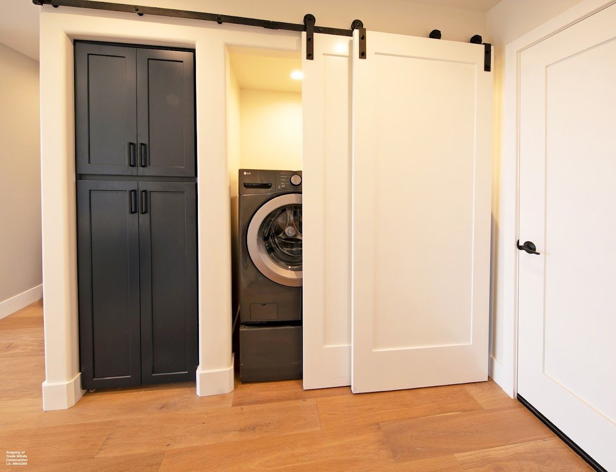 Laundry room with washer, navy cabinet, and white sliding door.