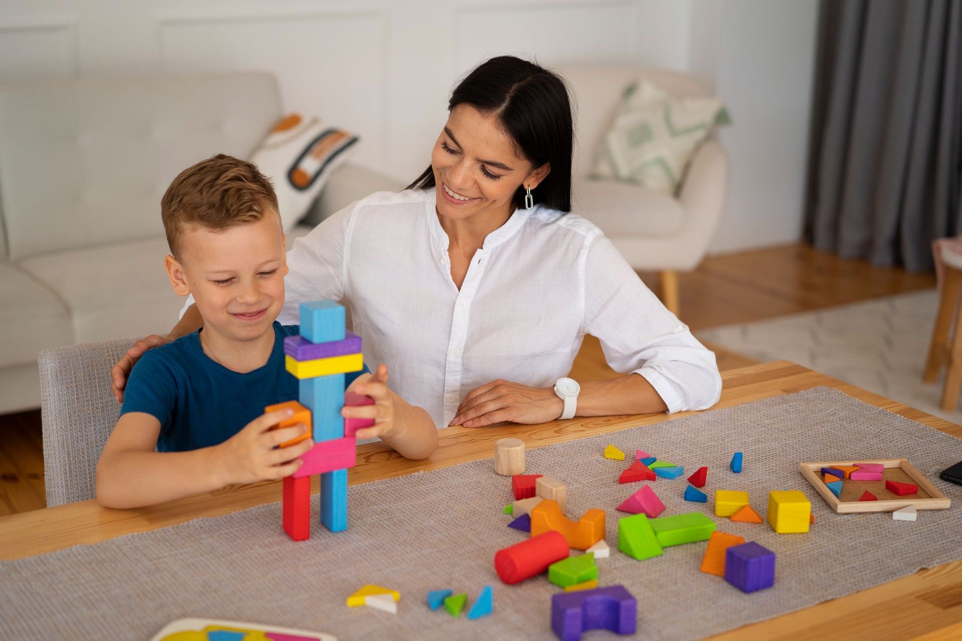 a woman and a child are sitting at a table playing with markers .