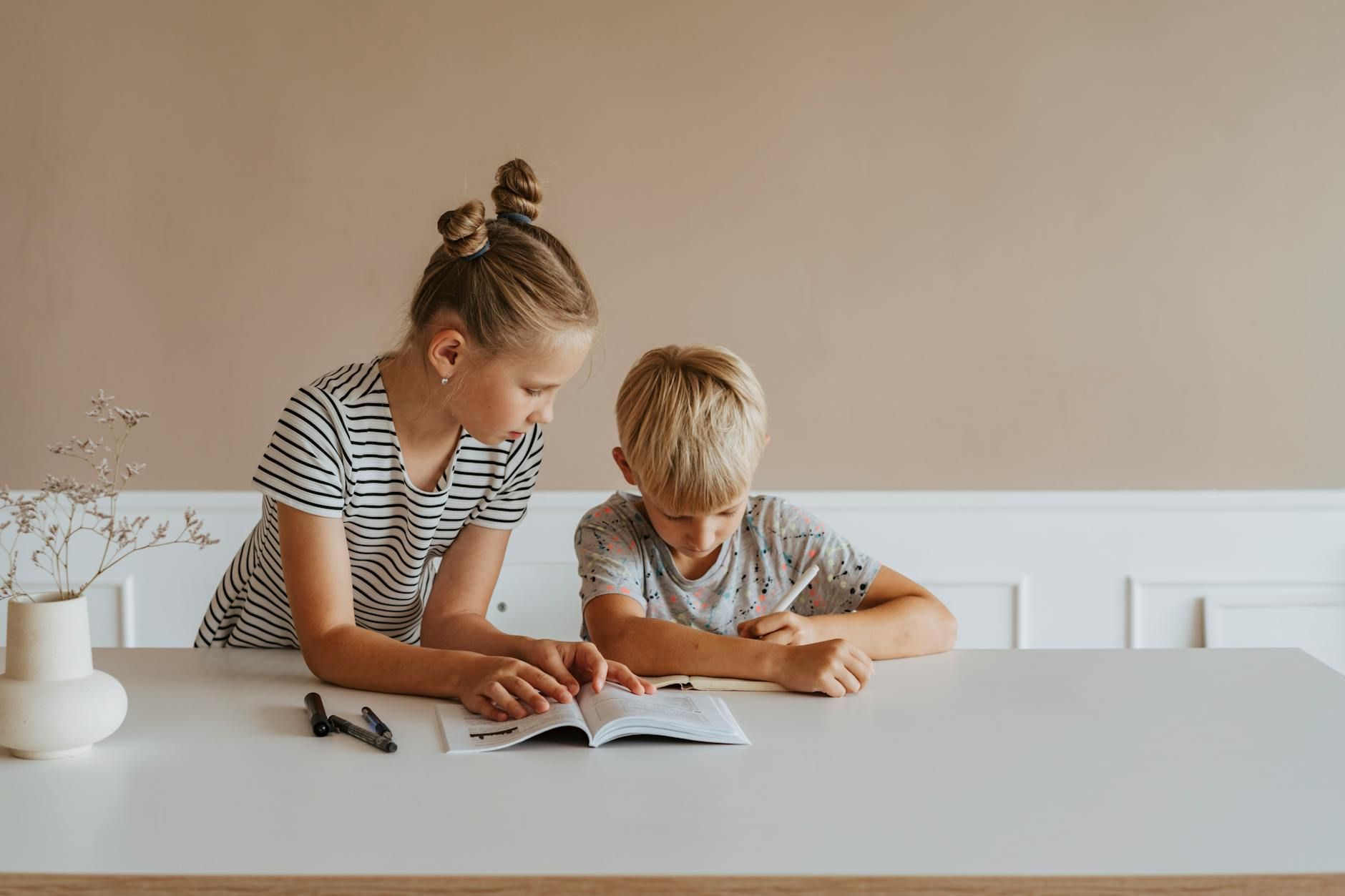A boy and a girl sitting on a table doing their homework