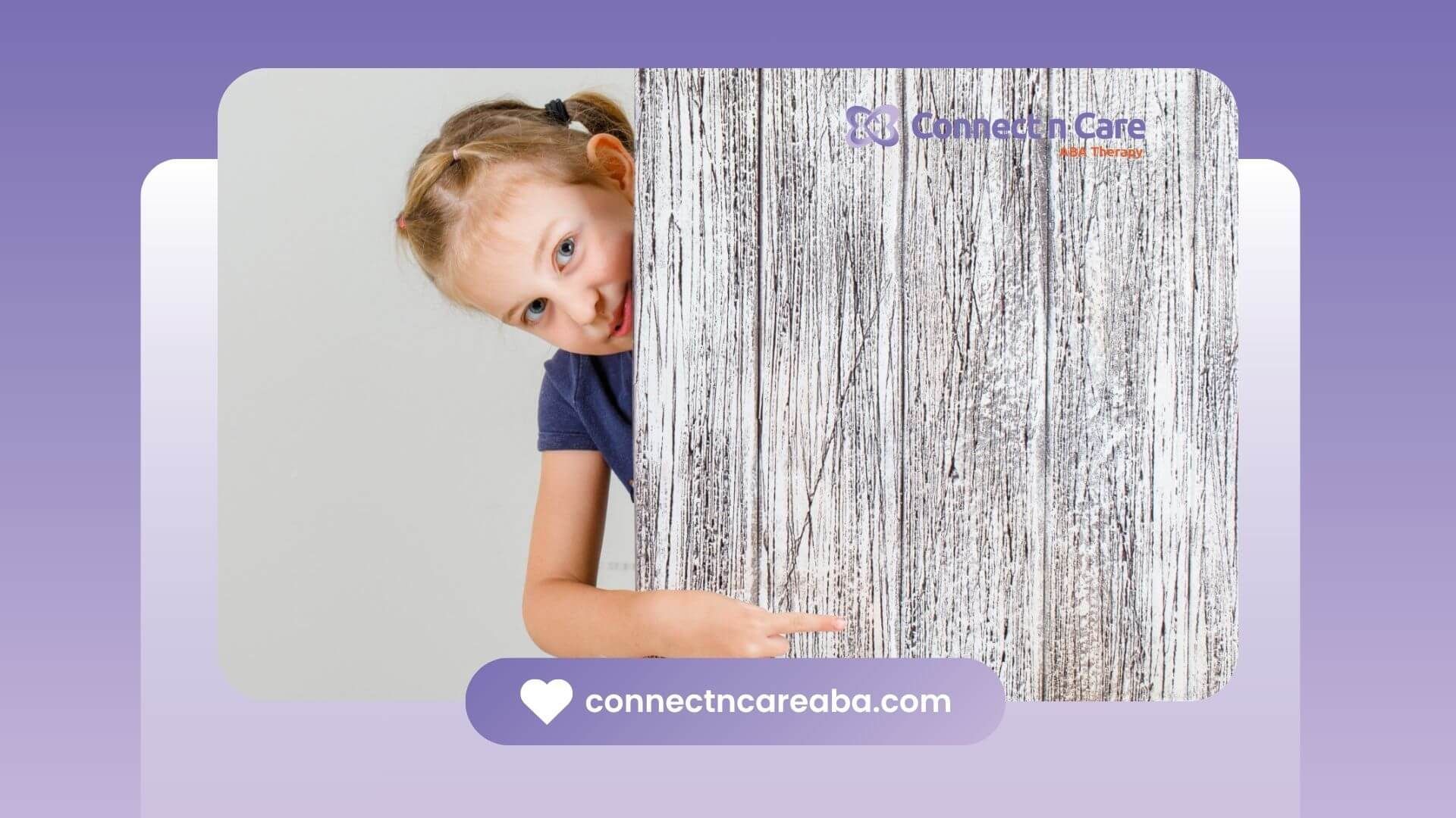 Little girl with autism peeking from behind a wooden board and pointing.