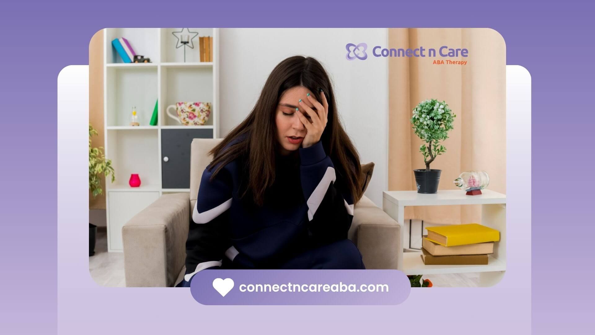 A woman is sitting in a chair covering her face with her hand.