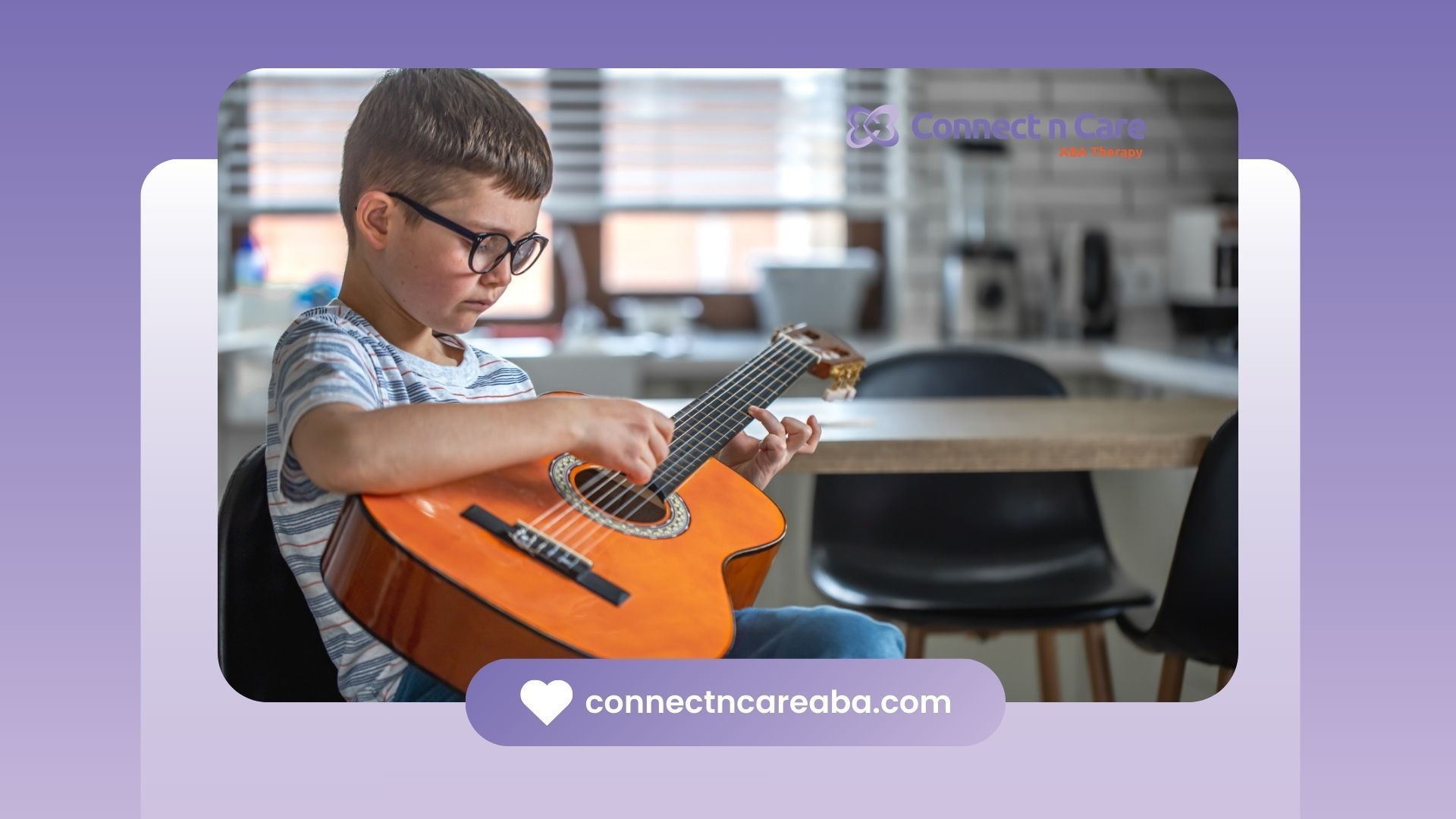 Boy with autism wearing glasses playing an acoustic guitar at a kitchen table.