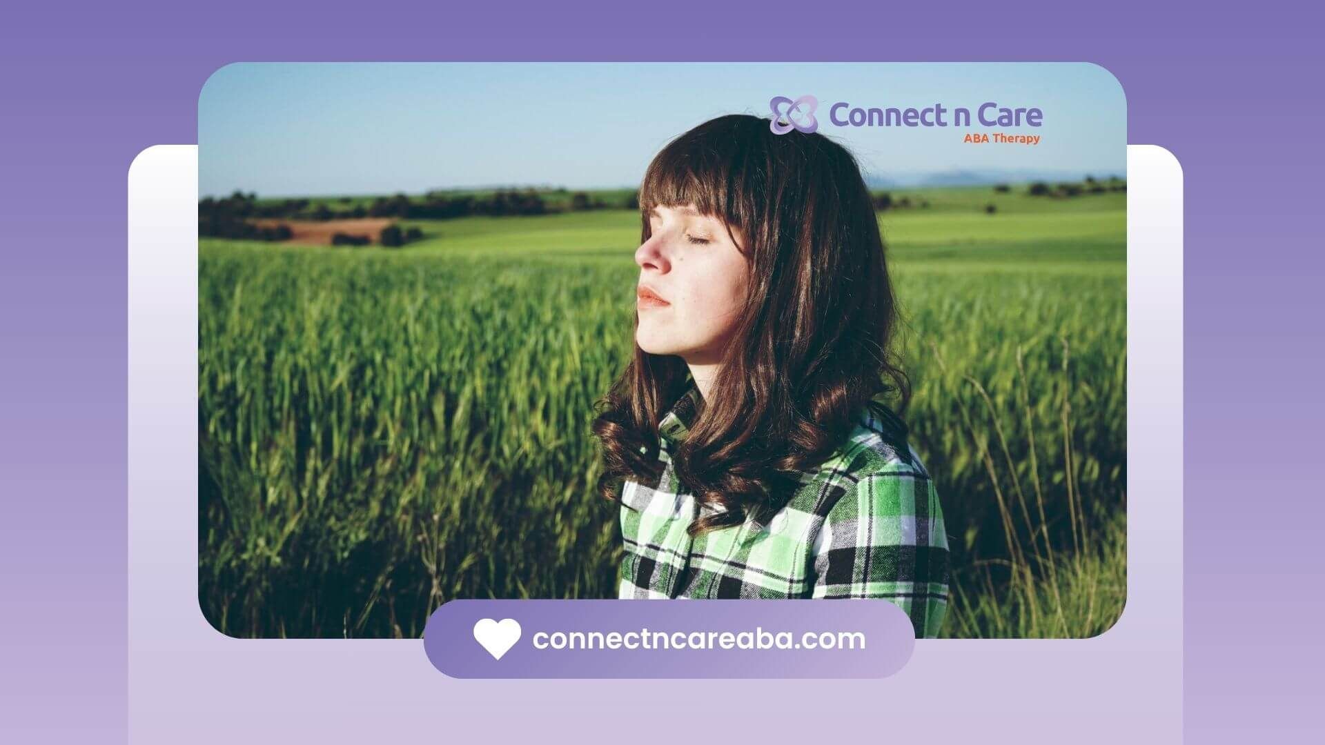 Girl with autism standing in a green field with eyes closed, enjoying nature.