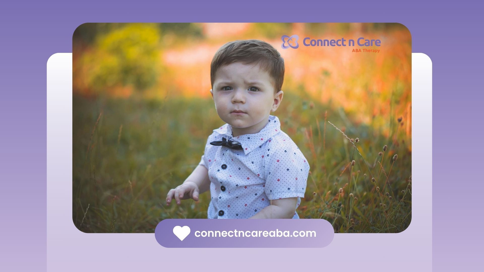 Little autistic boy sitting in a field in North Carolina with a serious expression on his face.