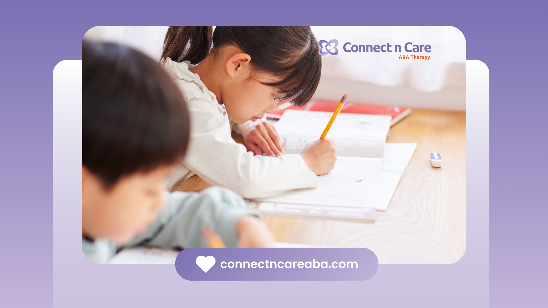 A boy and a girl are sitting at a table writing in a notebook.