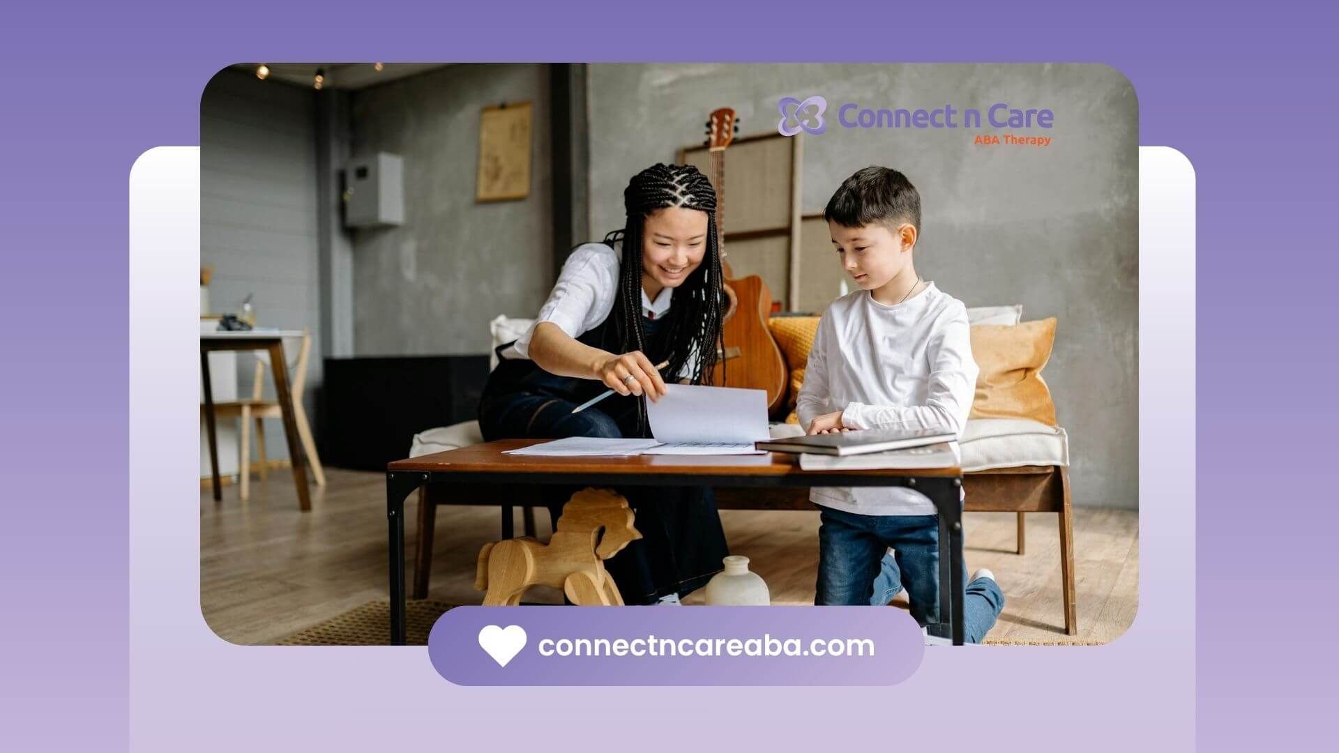 Smiling therapist woman tutoring the autistic young boy with books and papers on a coffee table.