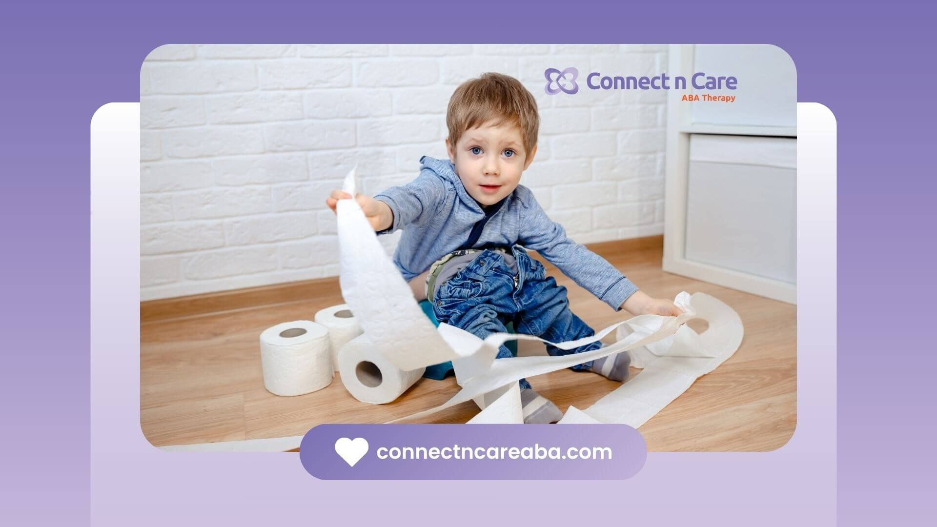 A boy playfully unrolling toilet paper on the floor, surrounded by rolls of toilet paper in a room.