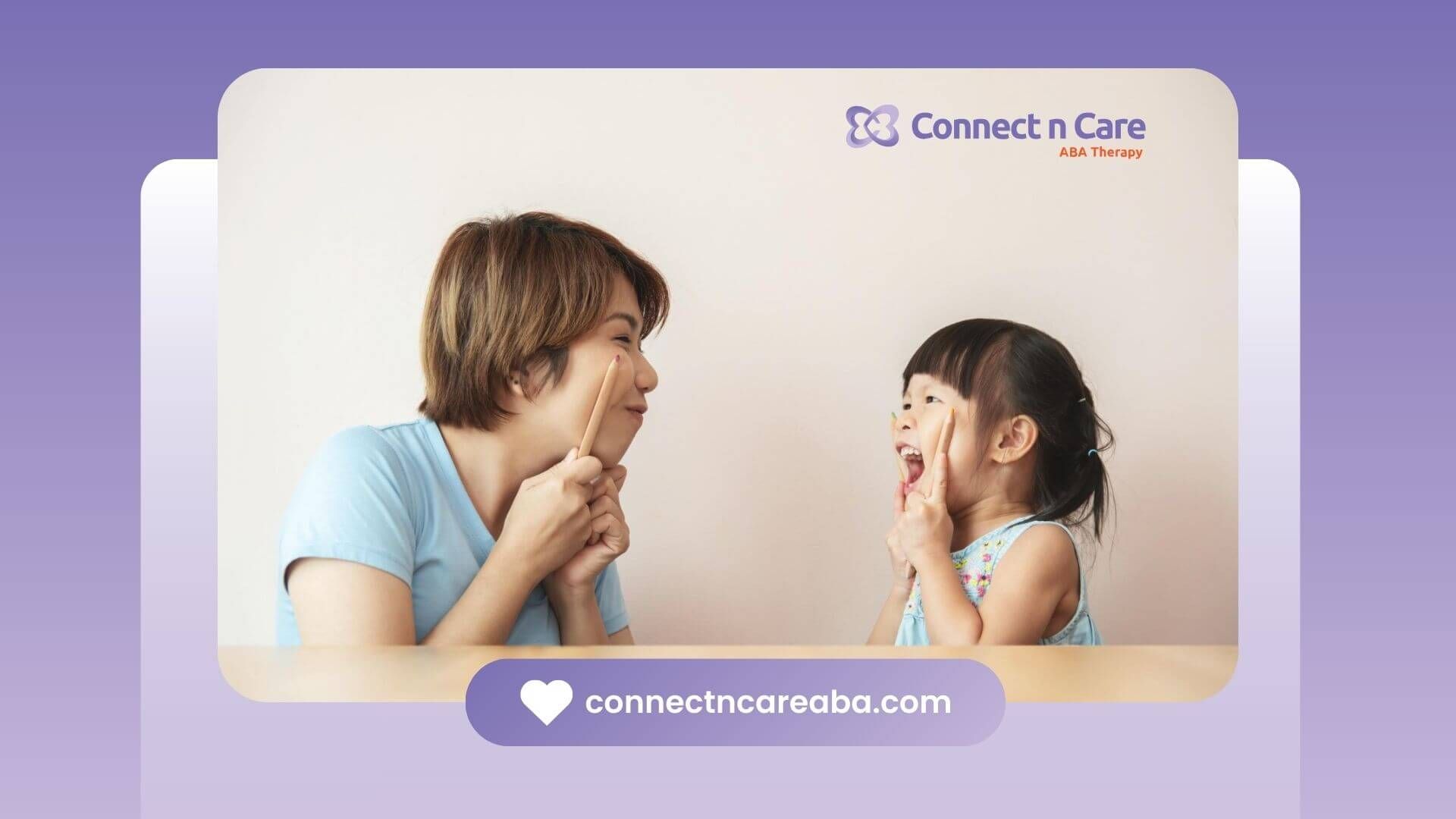 ABA therapist and autistic girl smiling and pointing to their cheeks.