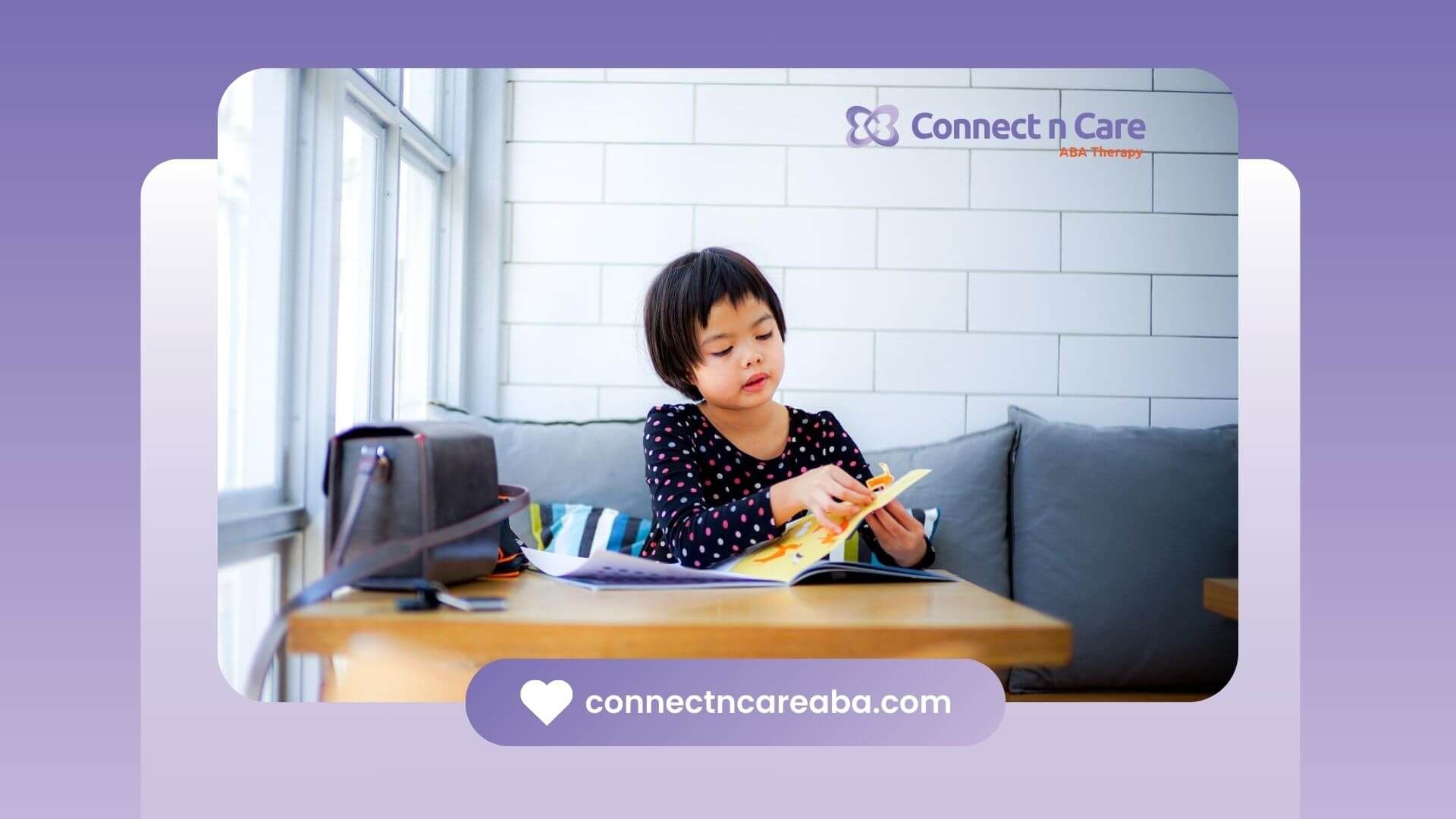 Young girl reading a picture book at a table by a window in ABA therapy.