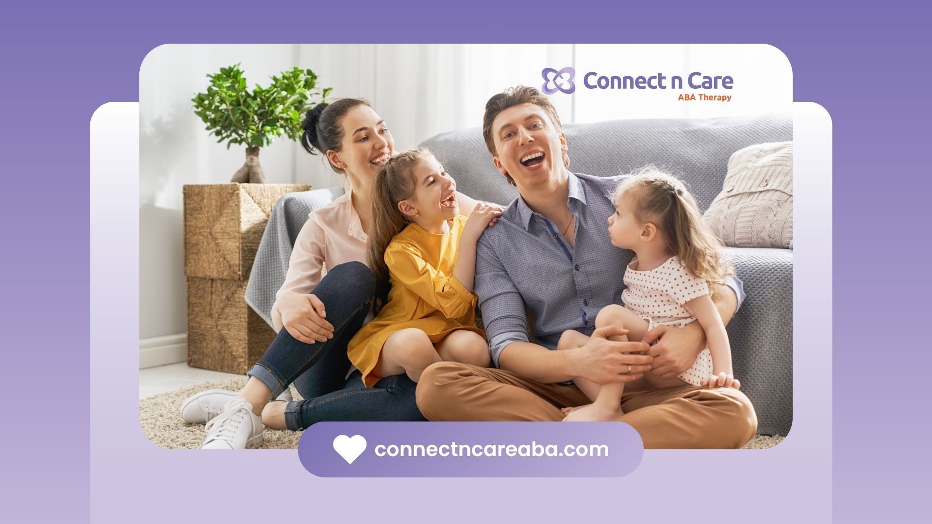 Family laughing together indoors, children sitting on parents' laps near a couch.