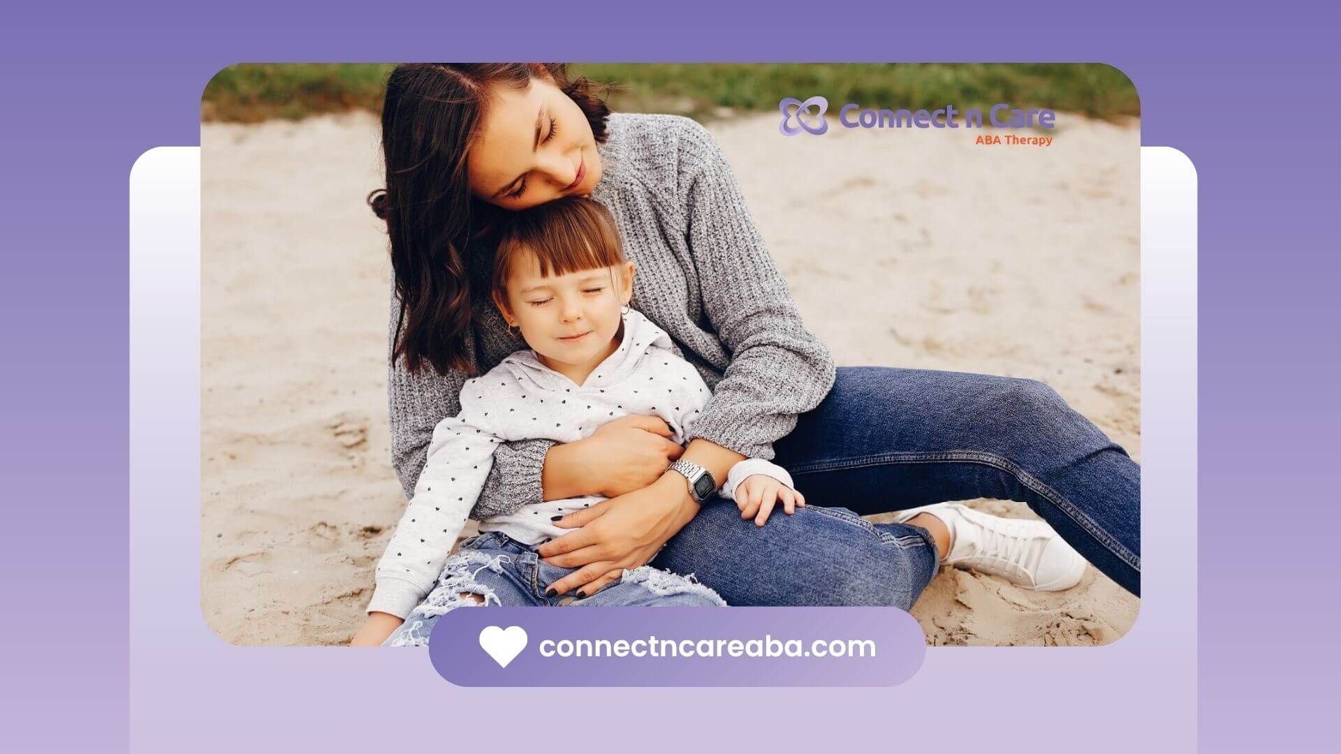 Therapist sitting on the sand while gently hugging young child with autism as they relax together.