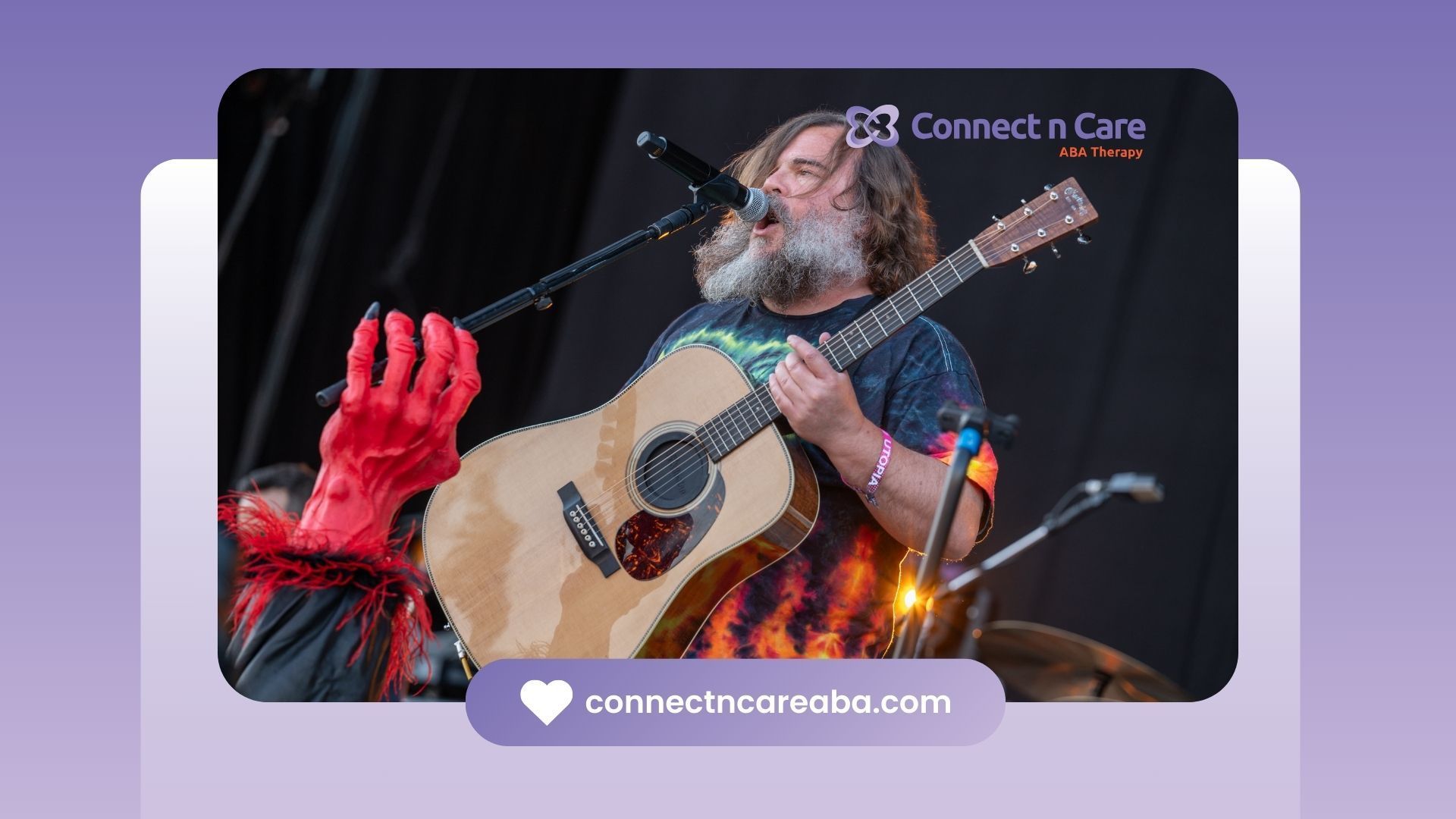 A man with a beard is singing into a microphone while holding a guitar.