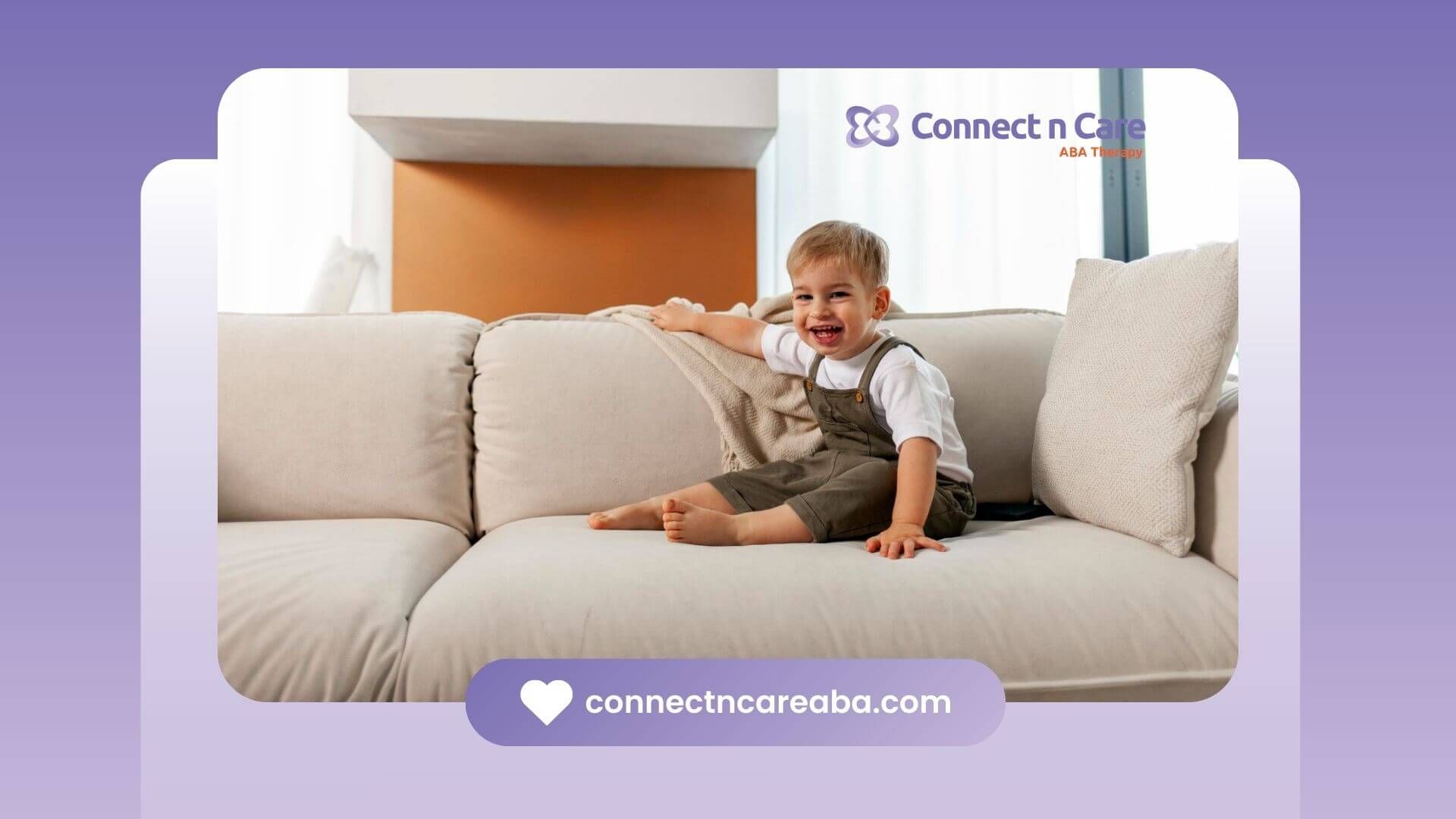 Smiling toddler with autism sitting on a beige couch in a bright living room.
