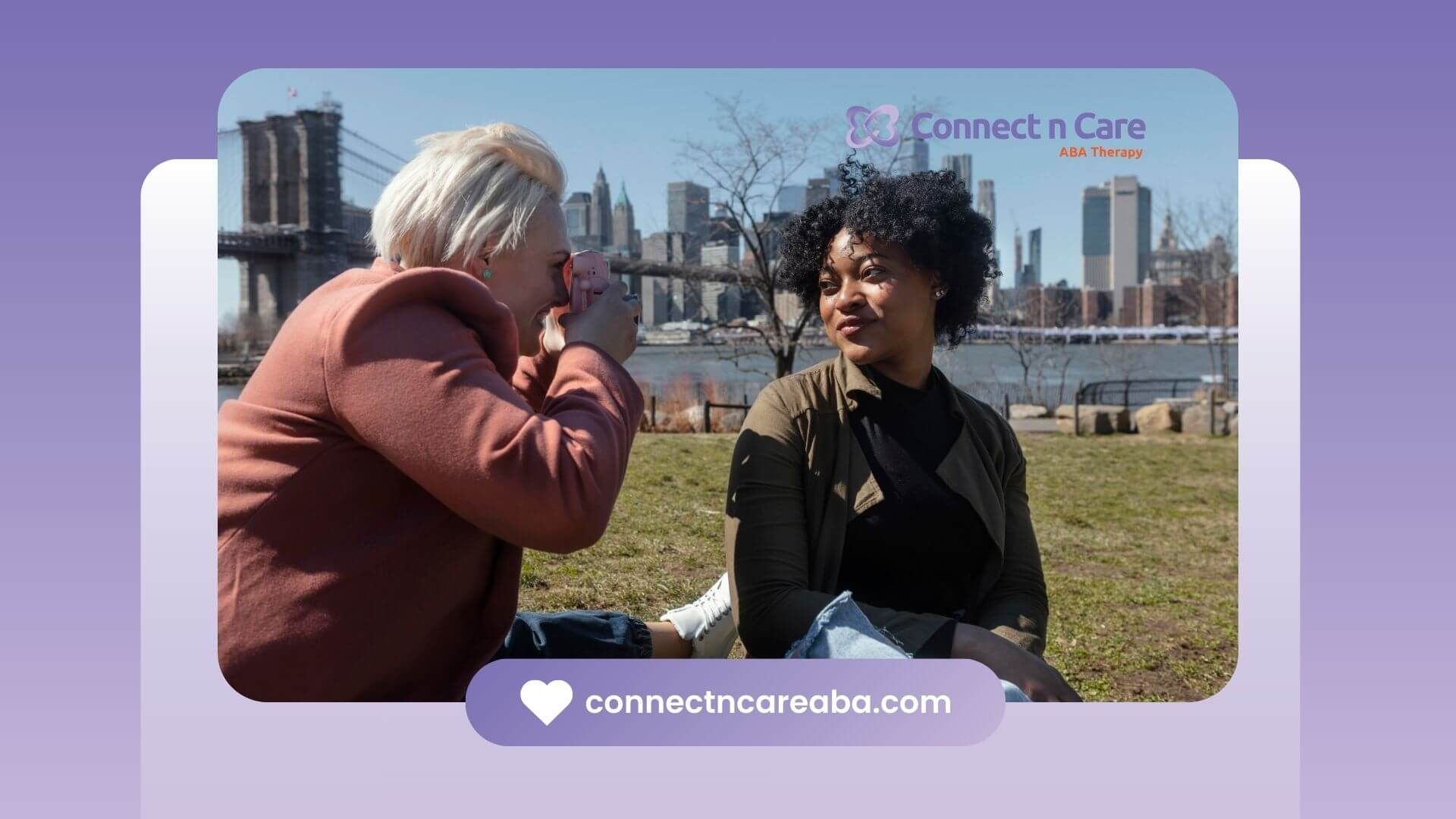 Two friends outdoors, one capturing a joyful photo of the other near iconic Brooklyn Bridge.