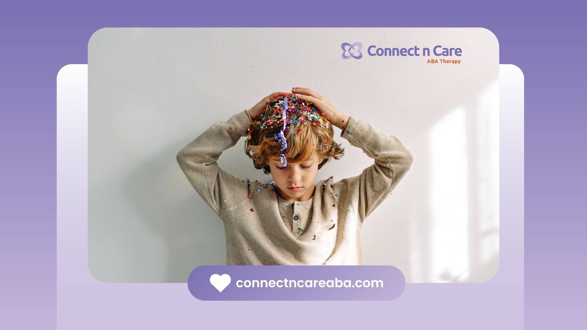A young boy with autism is holding a bunch of confetti in his hair.