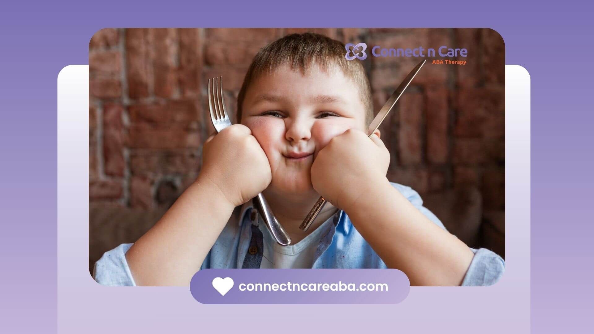 Smiling child with autism holding a fork and knife at a table.