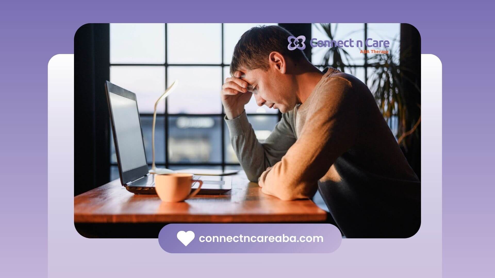 Autistic man sitting at a desk with a laptop, holding his head in stress or frustration.