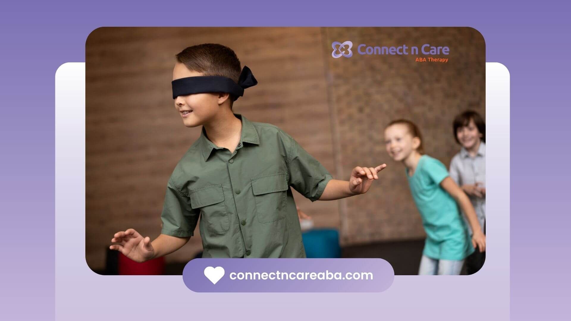A boy playing a game while blindfolded, smiling and having fun in a classroom-like environment.