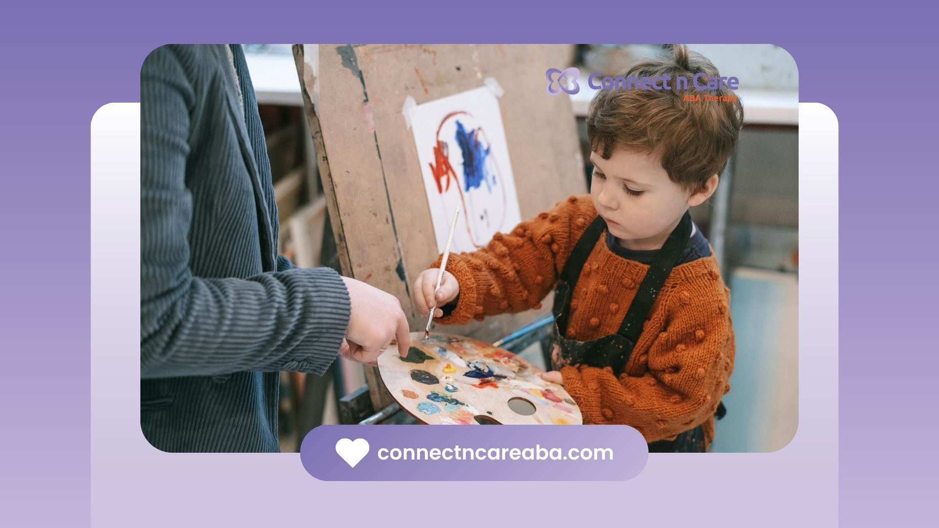 An autistic boy painting on easel with an RBT's help during ABA therapy in a sensory room in NC.