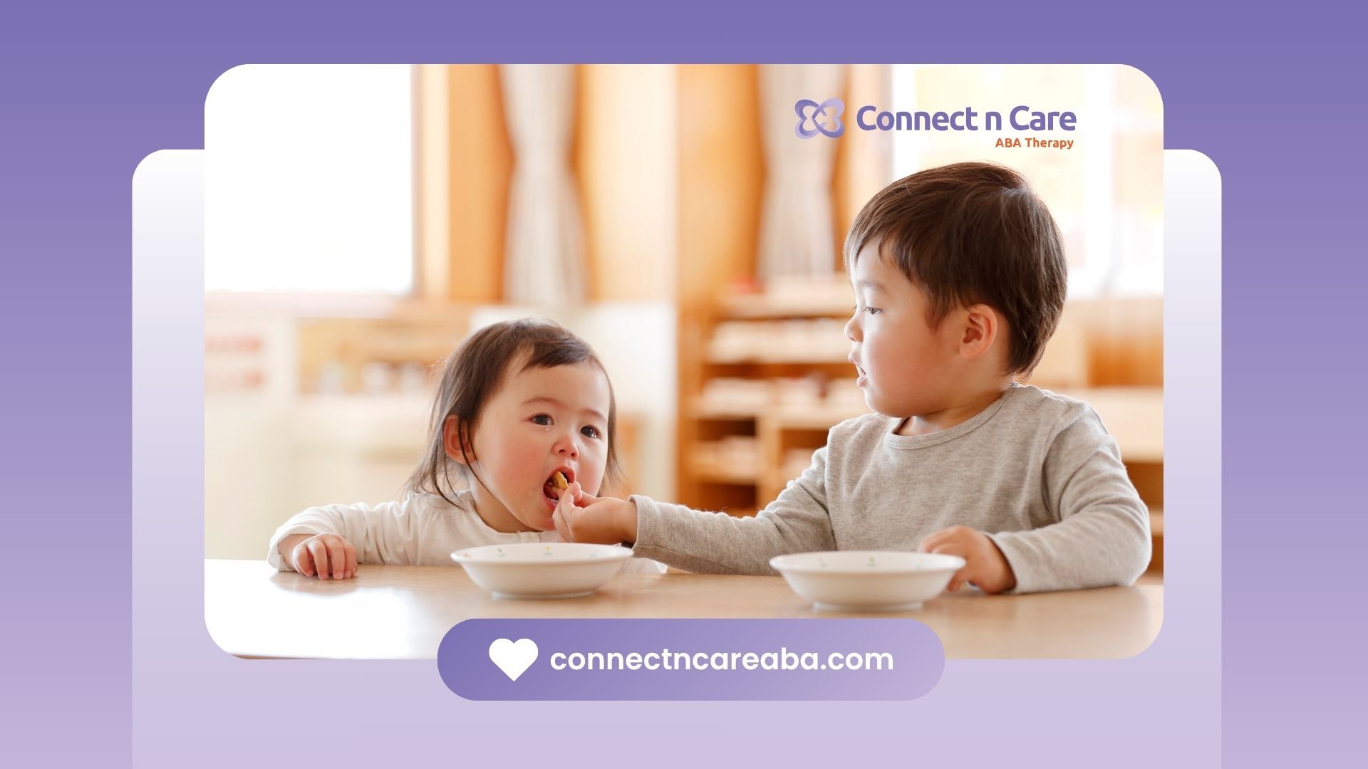 Boy feeding a girl as his sibling. Both are toddlers sitting at a table.