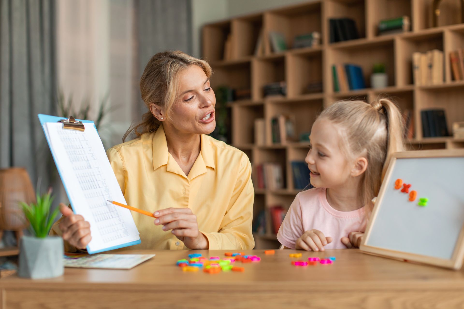 A teacher helping a little girl with her homework in a classroom