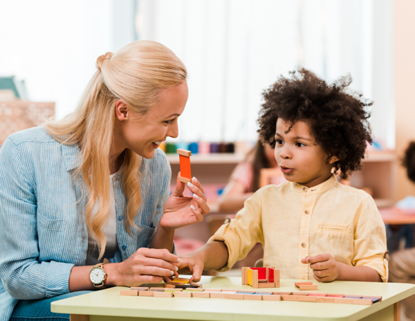 A woman sitting at a table with a young boy playing with wooden blocks
