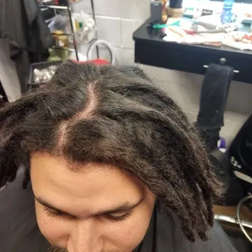 A close up of a man 's head with dreadlocks in a salon.