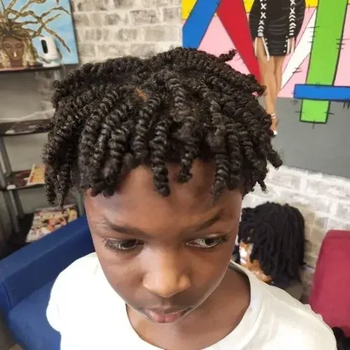 A young boy with twisted hair is wearing a white shirt