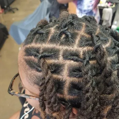 A close up of a person 's head with dreadlocks and glasses.