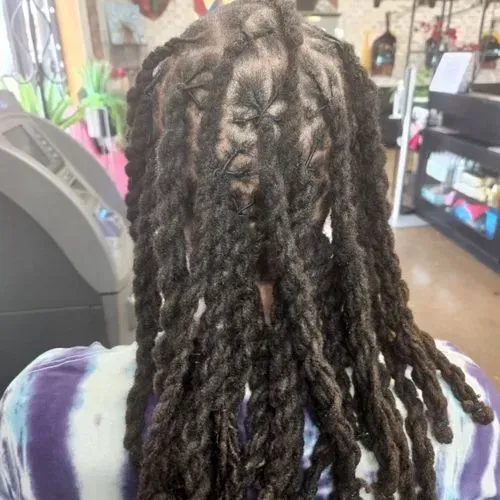 A woman with dreadlocks is sitting in a chair in a salon.